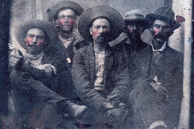 Billy the Kid and Pat Garrett sitting with three unidentified men