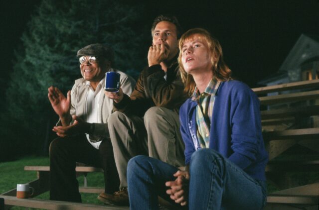 James Earl Jones, Kevin Costner, and Amy Madigan sitting on bleachers.