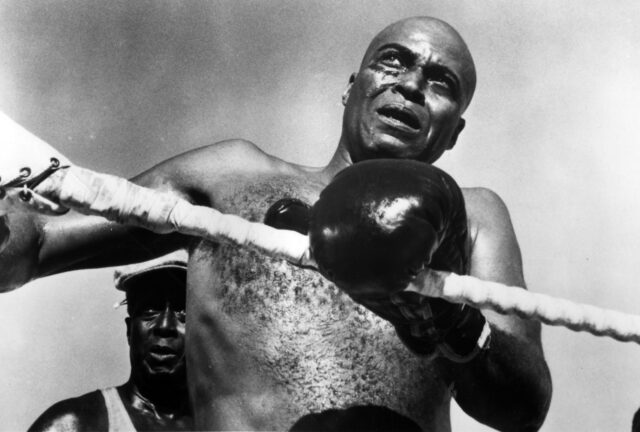 James Earl Jones as a boxer, wearing gloves and holding the ropes.