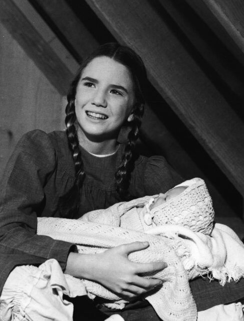 Melissa Gilbert holding a child in 'Little House on the Prairie' costume.