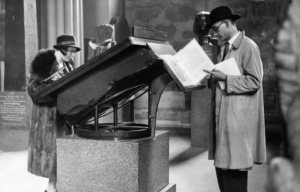 A woman looks at the Rosetta Stone as another man reads a paper.