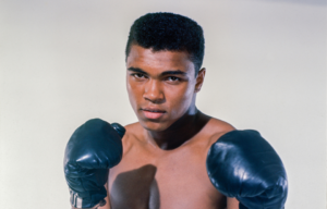 Cassius Clay holding up boxing gloves.