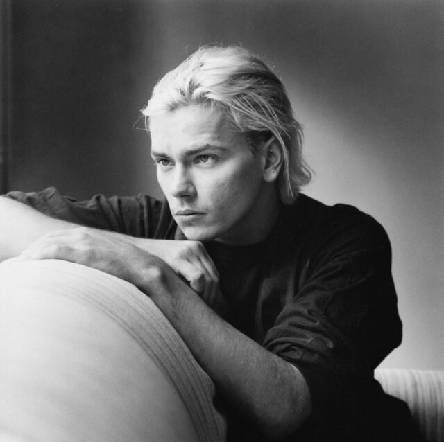 River Phoenix resting his chin on the edge of a cushion