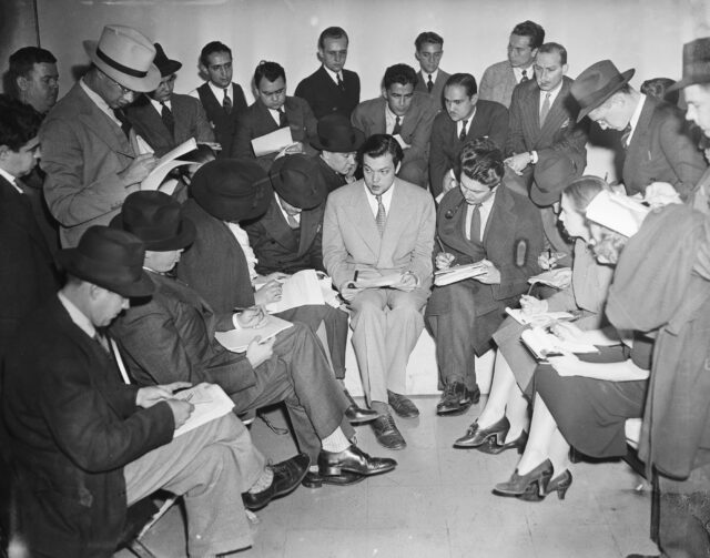 Orson Welles surrounded by reporters.