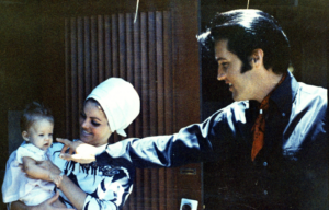 Priscilla Presley holding an infant Lisa Marie Presley, with Elvis Presley pointing at his daughter