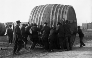 Men guiding a massive vat barrel.