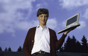 Bill Gates holding an early laptop.