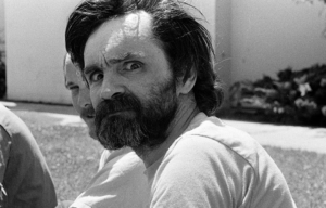 Charles Manson giving intense eyes to the camera over his shoulder.