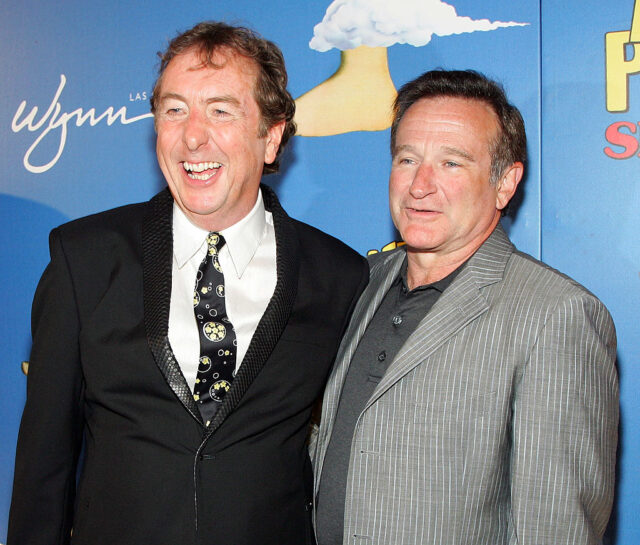 Eric Idle and Robin Williams standing together on a red carpet