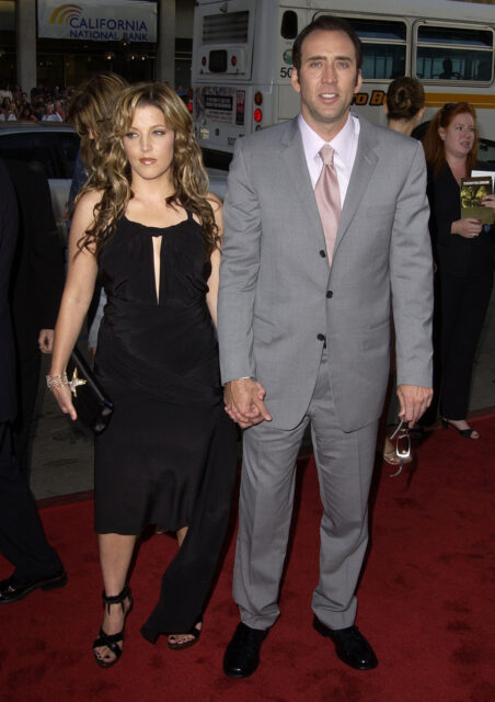 Lisa Marie Presley holding hands with Nicolas Cage on a red carpet.