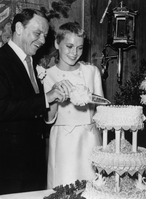 Frank Sinatra and Mia Farrow cutting a wedding cake together