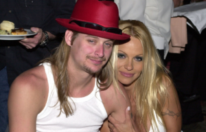 Pamela Anderson holds Kind Rock's arm as they pose for a photo together while seated.