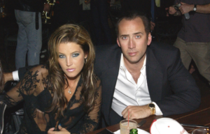 Lisa Marie Presley and Nicolas Cage sitting beside one another, posing for a photo.