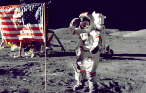 An astronaut walking on the moon beside an American flag.