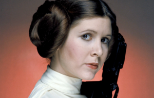 Headshot of Carrie Fisher as Princess Leia from 'Star Wars,' holding a blaster beside her head.