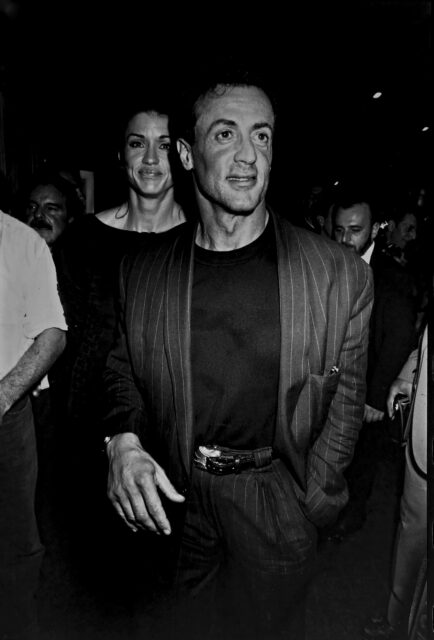 Sylvester Stallone walking through a crowd, with Janice Dickinson following him