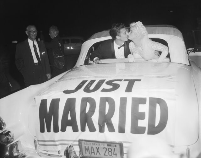 Jayne Mansfield and Mickey Hargitay leaning out the back of a car kissing that reads 'JUST MARRIED.'